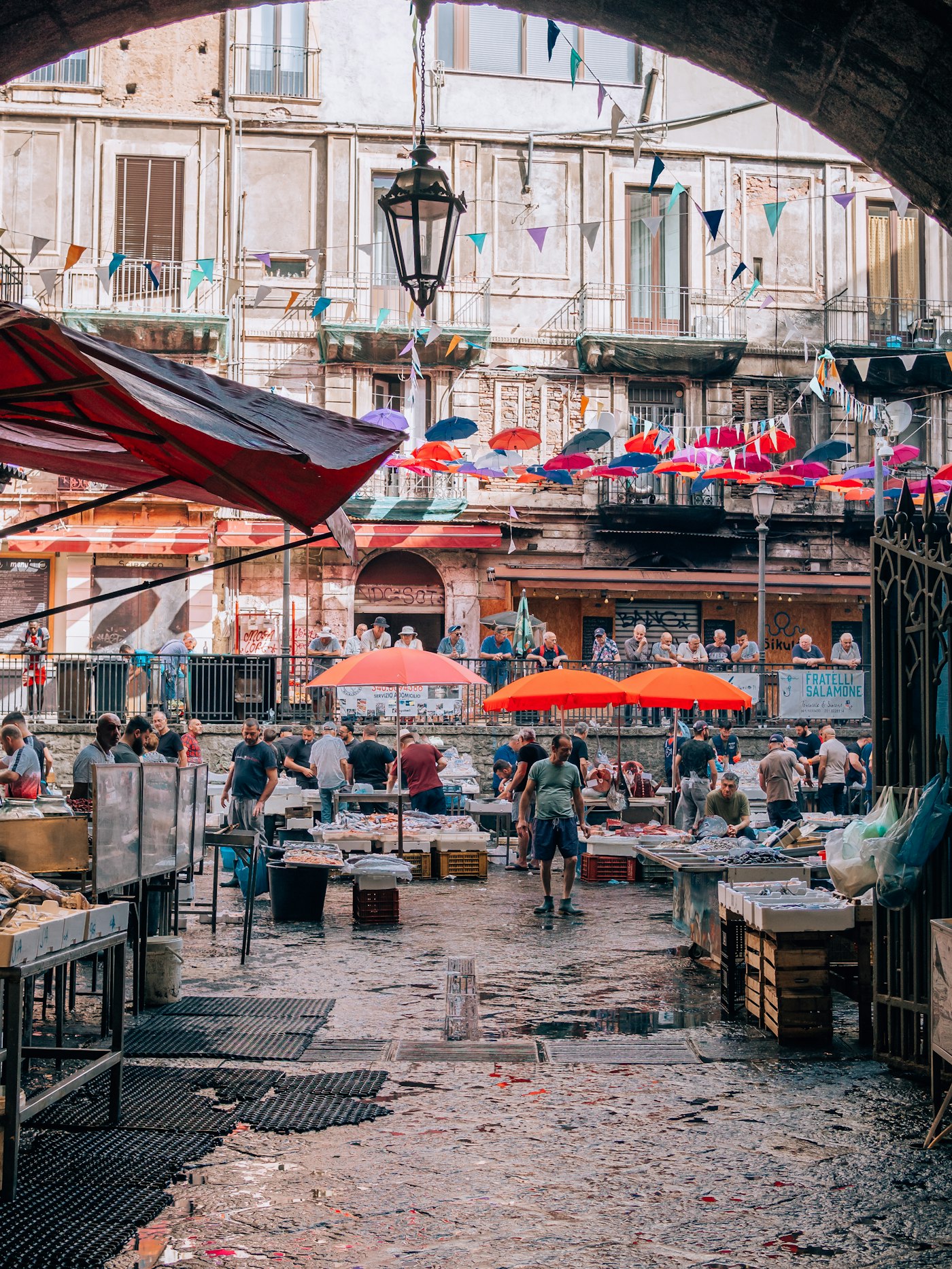 A bustling outdoor market with vendor stalls and colorful umbrellas